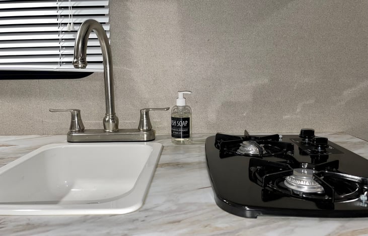 Large sink with two gas burning stove tops. Dish soap provided.