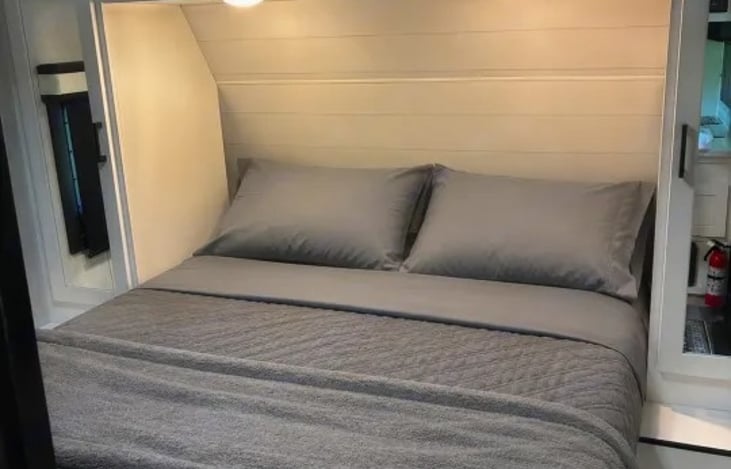 "Feathered Nest" offers a queen bed. A solid wooden pocket door slides shut to provide privacy from the rest of the camper.