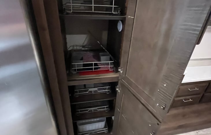 Large pantry with pull out shelves between kitchen and bedroom.