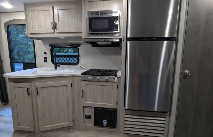 Indoor kitchen area with large sink, propane stove top, microwave, and fridge.