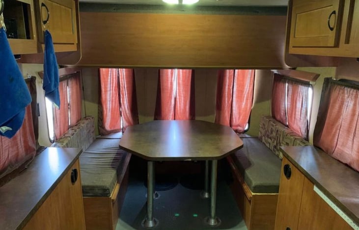 Interior of camper when standing with your back to the exterior door. Very roomy booth that can comfortably seat 6 adults! Folds down into a queen-sized bed. Full-size bunk above.