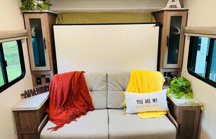 Closet storage with hangers and plugs on each side of the queen size murphy bed. With the bed up a comfortable couch to relax making the space feel spacious.