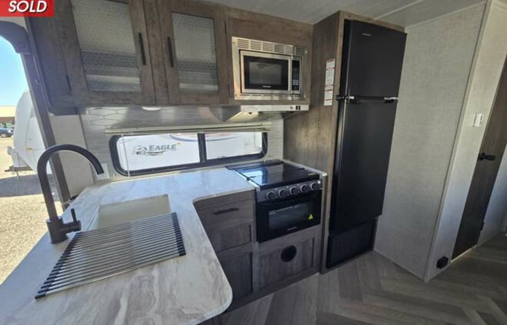 Double sink, storage, microwave, gas stove and oven, large freezer and refrigerator with shelves and drawers inside.