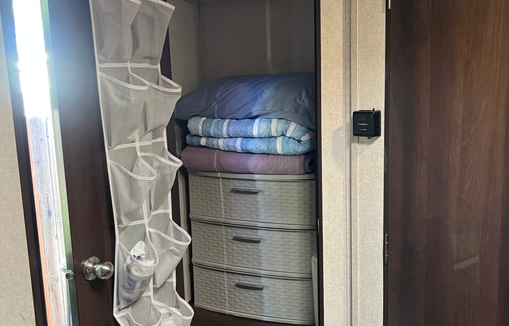 Inside the storage cabinet, where I keep the bedding. There is extra room in the cabinet for your belongings as well.