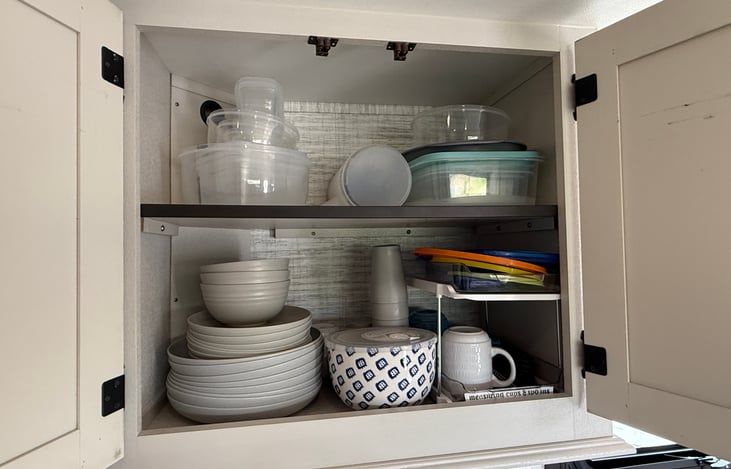 Cupboard stocked with all basic serving and cooking supplies.