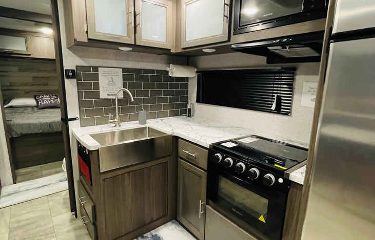 Fully furnished with dishes, this kitchen provides a stainless steel apron sink, 3 burner gas stove, gas oven, and 10 CF refrigerator with freezer.