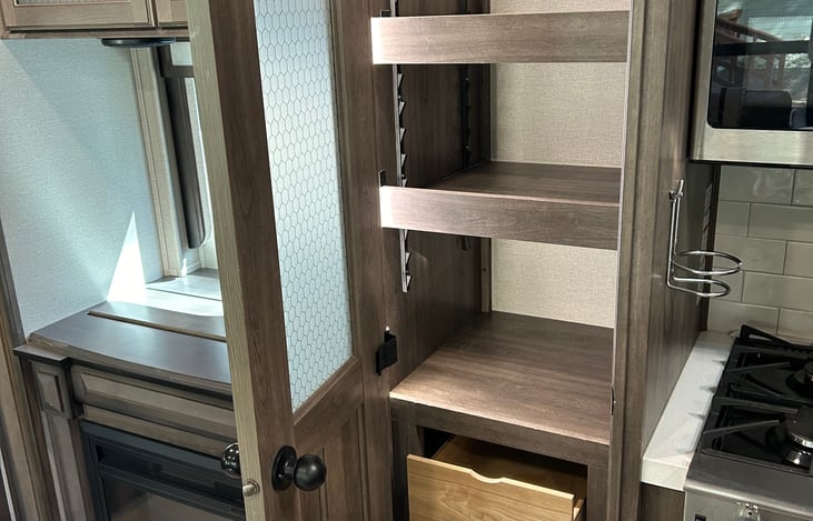 Pantry with three shelves and three drawers between stove and TV/fireplace