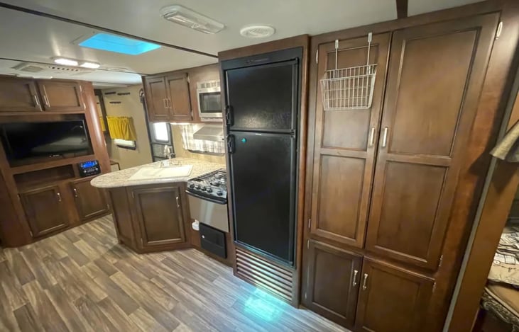 Kitchen has microwave, 3 burner stove, large sink, pantry and cookware storage. The exhaust fan helps to keep the odor out of the camper.