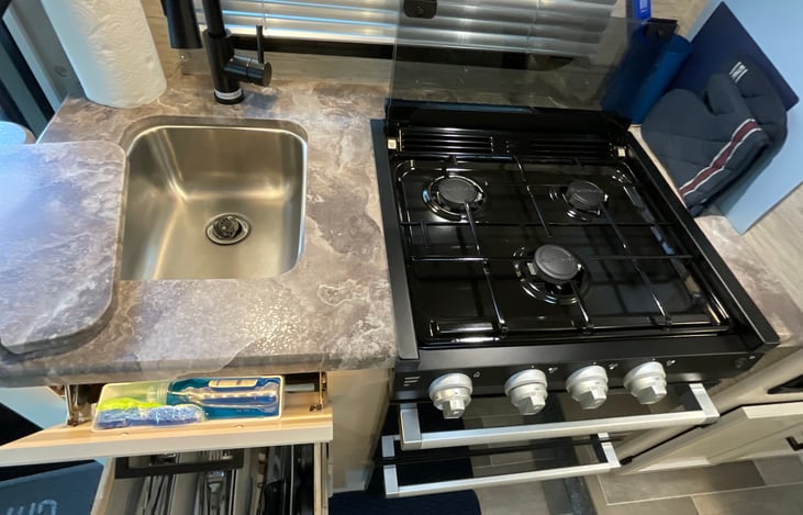 Three burner gas stove, dish soap, sponge and paper towel roll included.