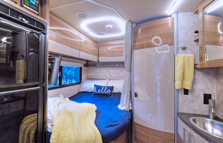 View of the queen sized bed. Full size refrigerator and freezer