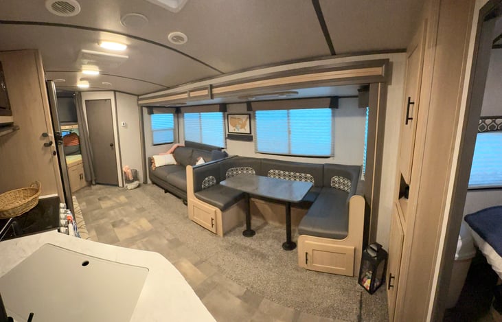 Wide, comfortable walkway with full standing height, overhead lighting, and multiple AC vents, leading past a fully stocked kitchen with large fridge/freezer to two full-size bunk beds in the rear.