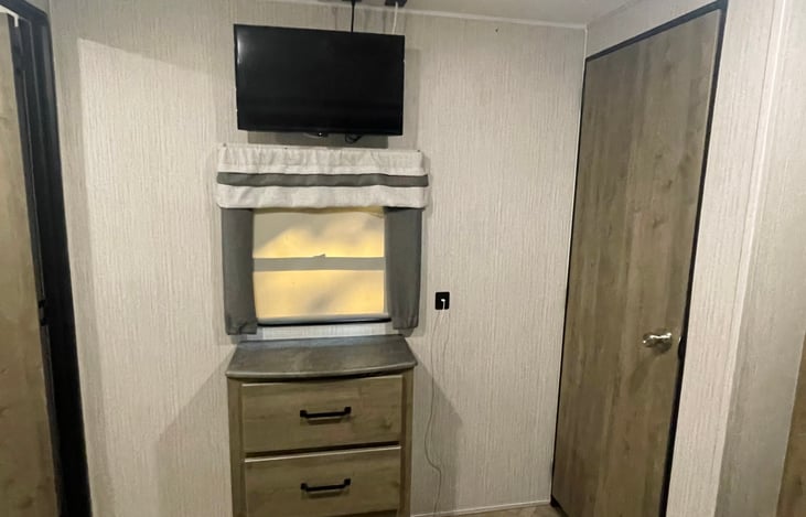 Private master bedroom has tv and dresser.