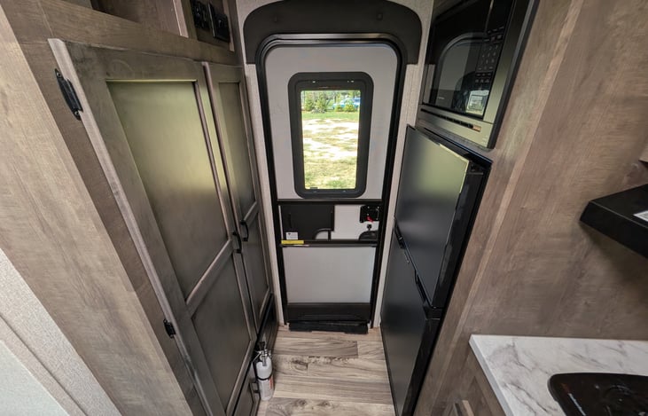 Spacious rear kitchen layout with ample counter space, double-door fridge, stove, microwave & deep sink. Perfect for prepping campsite meals with all the comforts of home!