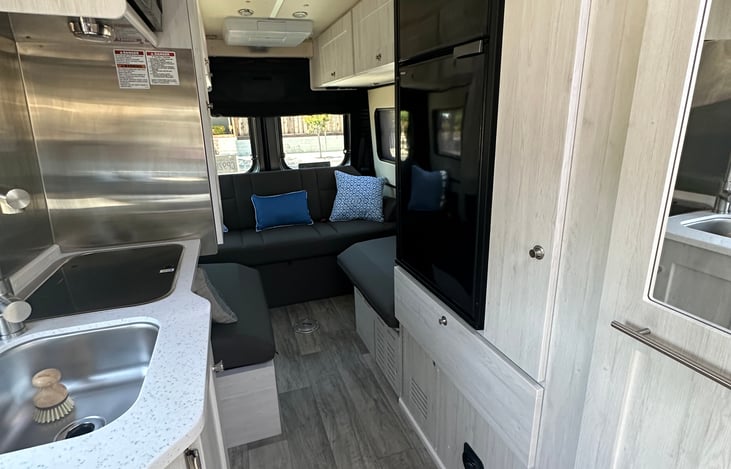 Entering the van, the bathroom is on the right and the kitchen with everything you need (fully stocked, microwave, refrigerator, freezer, two burner propane stove, electric kettle, coffee maker)