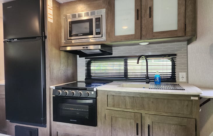 A big 12 volt fridge, a 3 burner cook top plus an oven. A microwave and a dual sink with a drying rack.

We provide basic cookware and utensils.