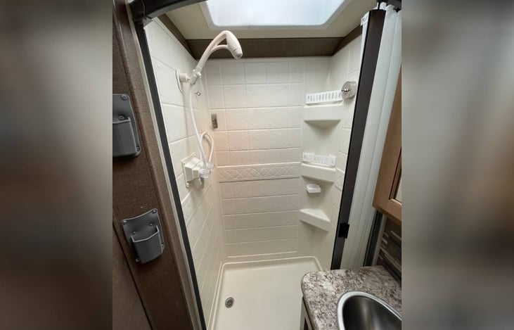 Shower has skylight and built in curtain.