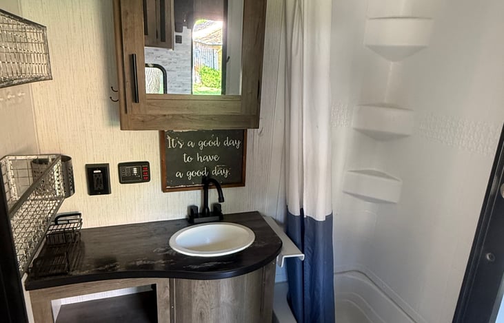 Typical camper bathroom. Shower, sink, toilet, countertop and storage. A residential door has been installed to replace the usual camper bathroom door.
