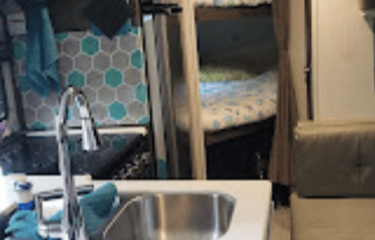 Fully equipped indoor kitchen includes full size 12 volt refrigerator, microwave, double sinks, power station, cooktop and oven.