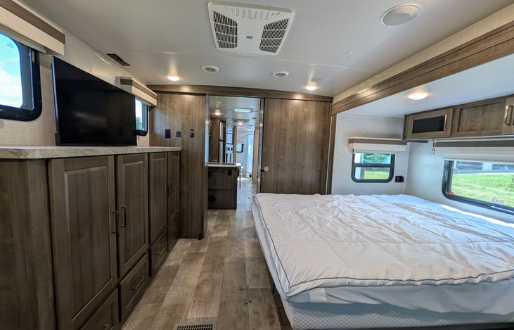 Private front bedroom features a walk-around Queen bed, TV, ample wardrobe storage, and a cozy built-in window seat nook—perfect for relaxing with a book! Full of natural light from 6 windows.