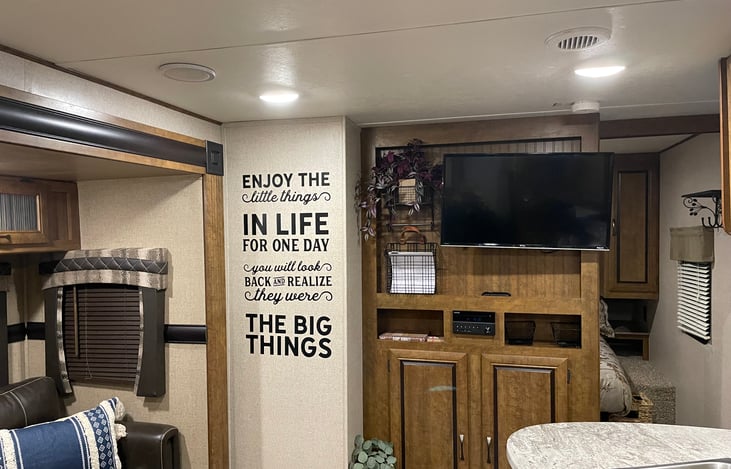 TV, CD Player and Radio, with cabinet holding Instant Pot, Camping Lantern, Small Crock Pot, Telescopic Skewers, 2 small propane canisters for outdoor grill provided.    RV Manual included.