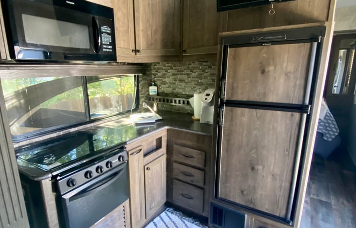 Microwave, 4-top gas burner, oven, two compartment sink, freezer and refrigerator. TV above refrigerator.