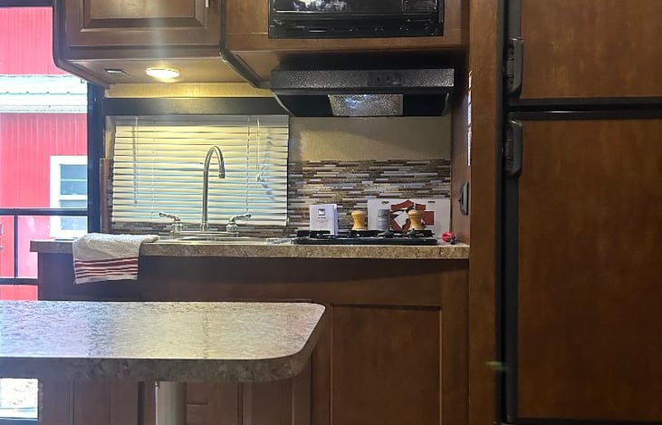 Kitchen with microwave, 2 burner stove and refrigerator(runs on gas or electric). Exhaust hood vent to exterior. Also has a two basin sink.