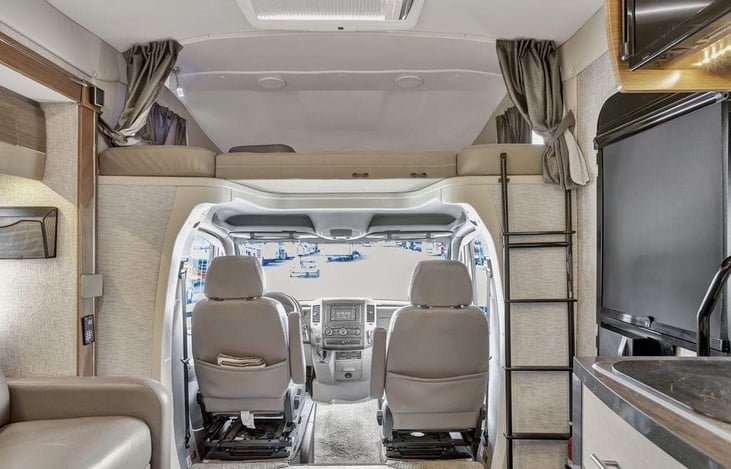 Driver area; both seats can be rotated to face the rest of the group when hanging out. Stairs leading to overhead bunk.