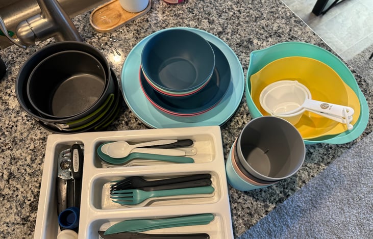 Reusable silverware, big and small plates, bowls, mixing bowls, cups, and 2 small pots and 2 small plans  are included for your convenience. Not pictured but incl. is a grater, peeler, and can opener!