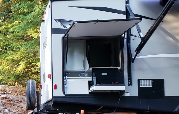 2 Burner propane stove and sink with cabinets and a light inside on ceiling. If plugged in mini fridge works also.