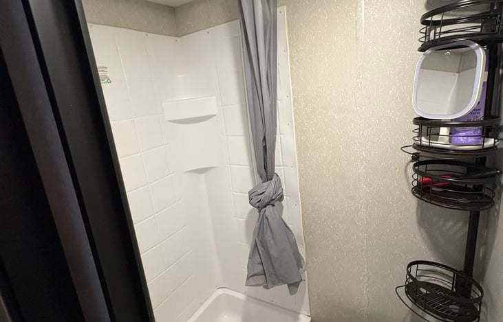 Bathroom with shower, sink, vanity, mirror and storage.