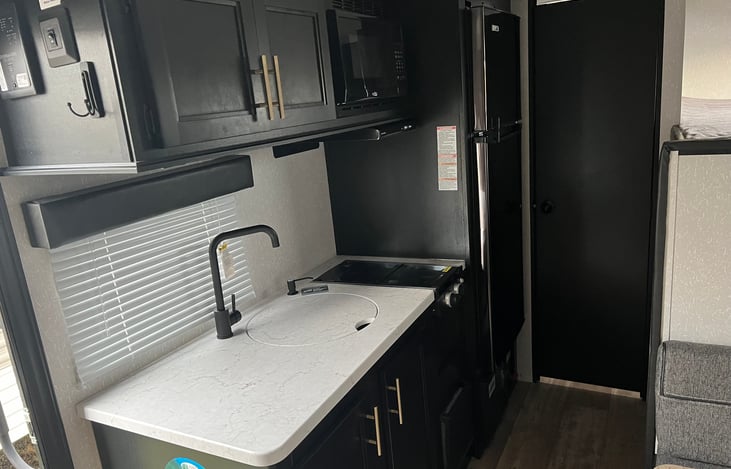 Microwave, stove and kitchen sink. Looking back, we have the refrigerator and restroom area.