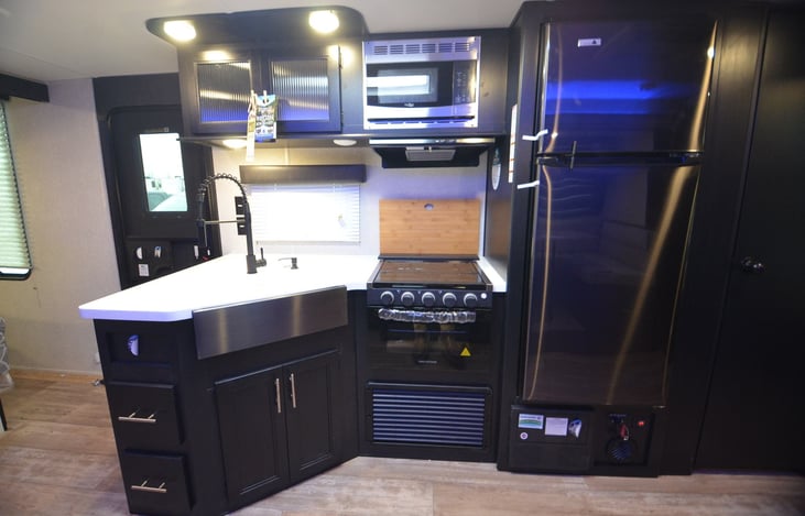 Kitchen has large fridge and separate freezer, double-sink, microwave, 3-Burner stove, oven, magnetic cutting board, knife rack, Keurig coffee maker. Built-in dish soap dispenser/hand-sanitizer.
