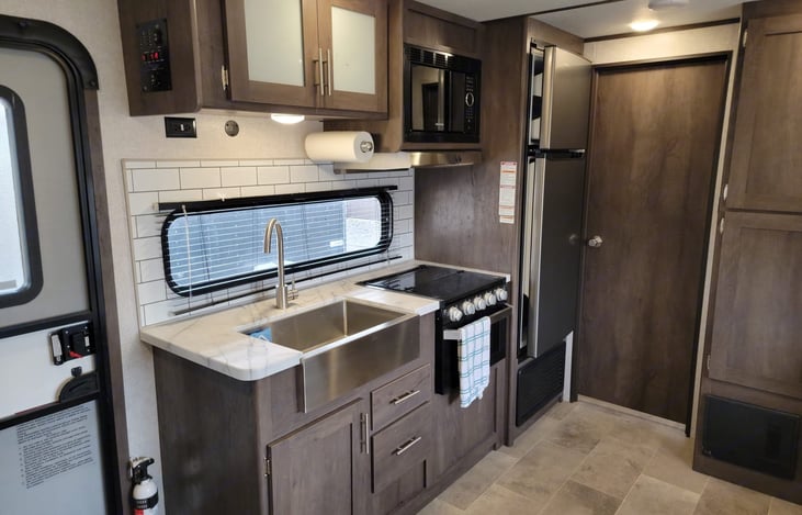 Farm style sink, microwave, 3 burner propane cooktop, oven, large refrigerator and freezer.