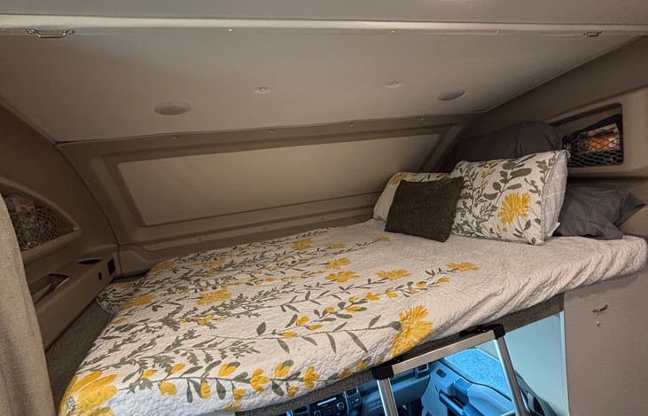 Queen bed with a privacy screen that is over the driver and passenger seats.