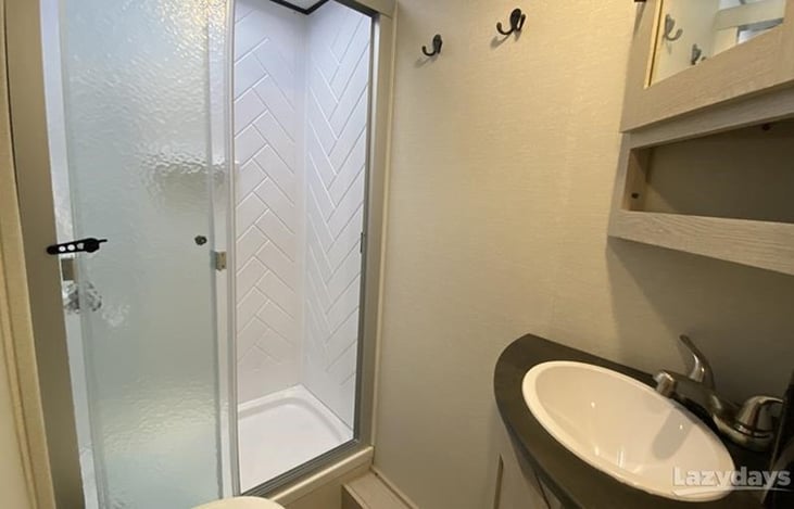 Toilet, sink with mirrored medicine cabinet and shower with sliding glass door and skylight