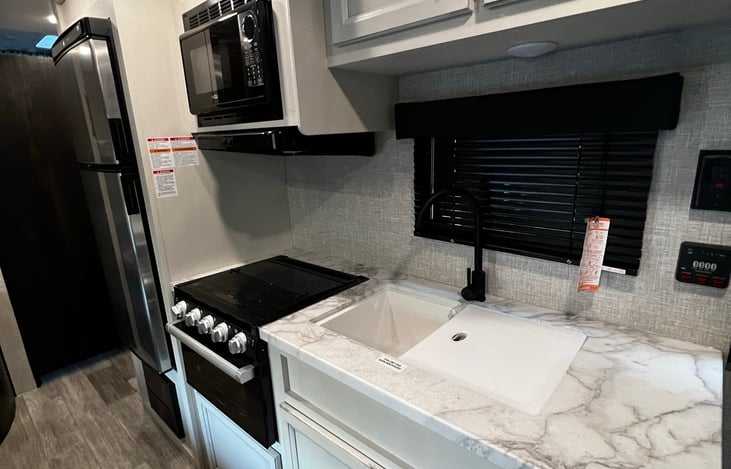 Kitchen w/ 3 burner stove, microwave, double sink, full size fridge and many cabinets.