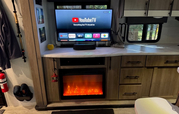 Retractable TV lifts up for viewing and lowers for storage. The TV is connected to the RV’s rooftop antenna for local channels and to Wi-Fi for streaming through Roku and Apple TV. A surround sound ba