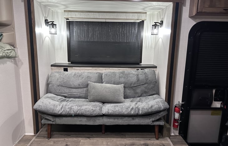 TV is on an elevator behind the futon.