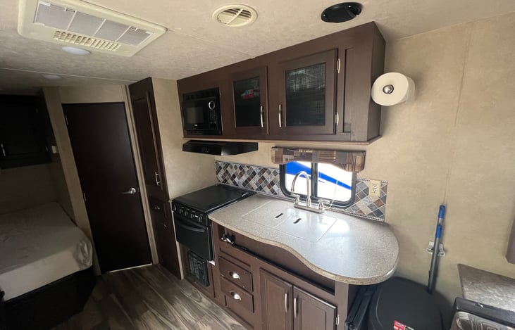 Sink, stove/oven and microwave with cabinets for storage.