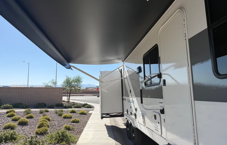 Primary side with awning and outdoor kitchen slide.