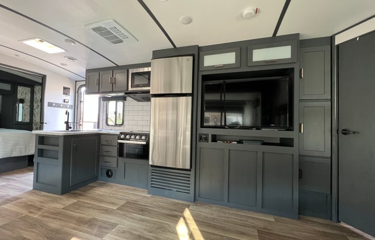 Kitchen view. Large sink, microwave, 3 burner stove top, oven, and refrigerator.