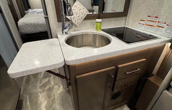 View of kitchen area with uncovered sink and counter top extension out.