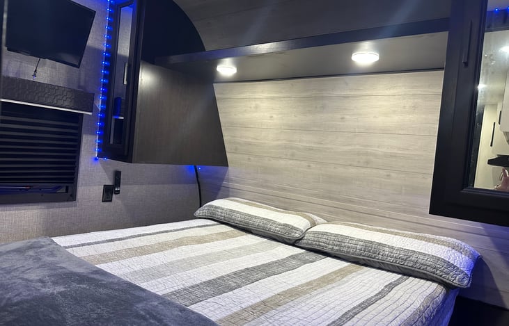 Primary Room with doors for privacy. This room features a queen bed, storage shelfs, rod for clothes, and two nightstands.