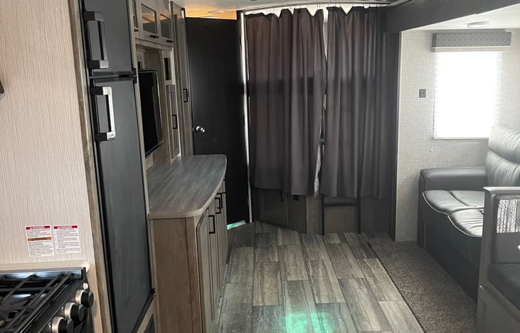 Inside the RV area with queen size bunk beds, sofa. Bunk beds have a curtains for privacy