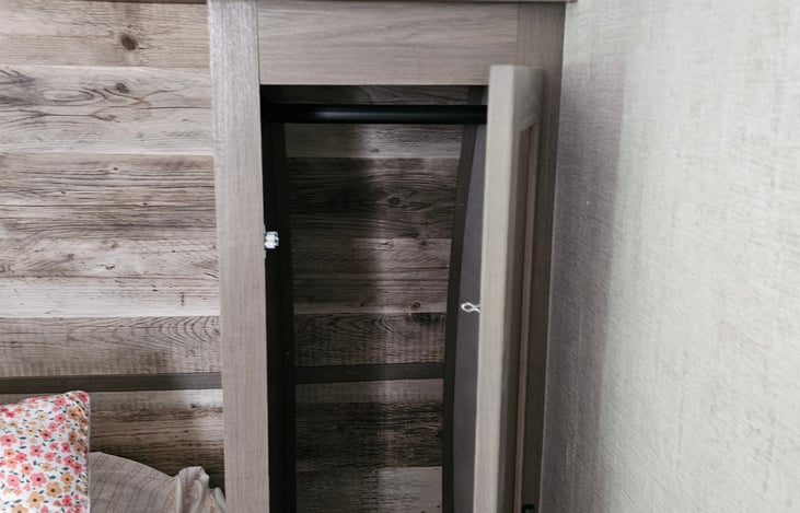 Storage space next to Queen Size Bed with rod to hang up clothes you don't want wrinkled.