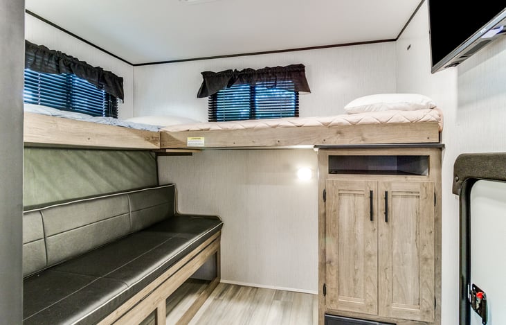 Bunk room showing queen bed folded up and couch area with tv in room for kids.