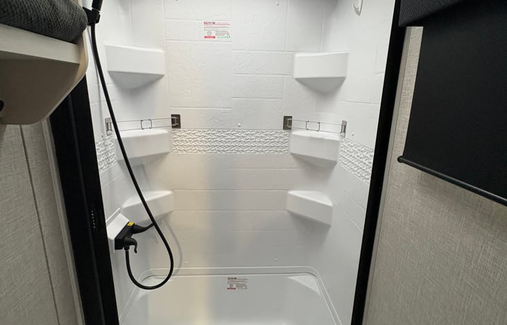 6 foot shower head with rolling door (no curtain) and shower hooks for wet clothes.