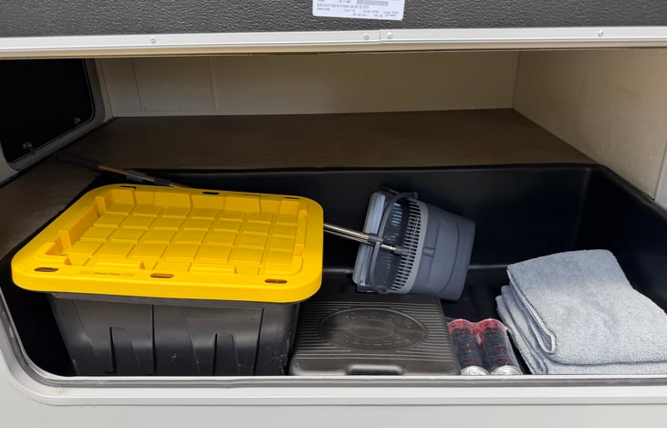 Main Storage. Includes Sewer hose in container, Broom and Pan, Utility towels, Exterior Butane Stove with extra Butane.