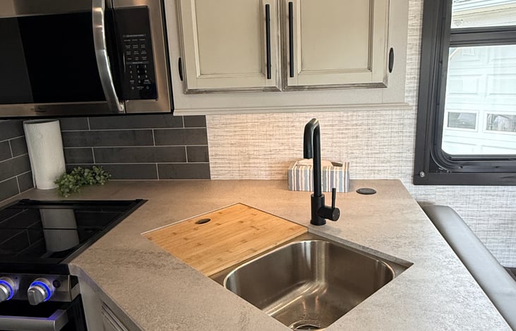Stainless steel sink with cover for one side and roll up grate for other side.