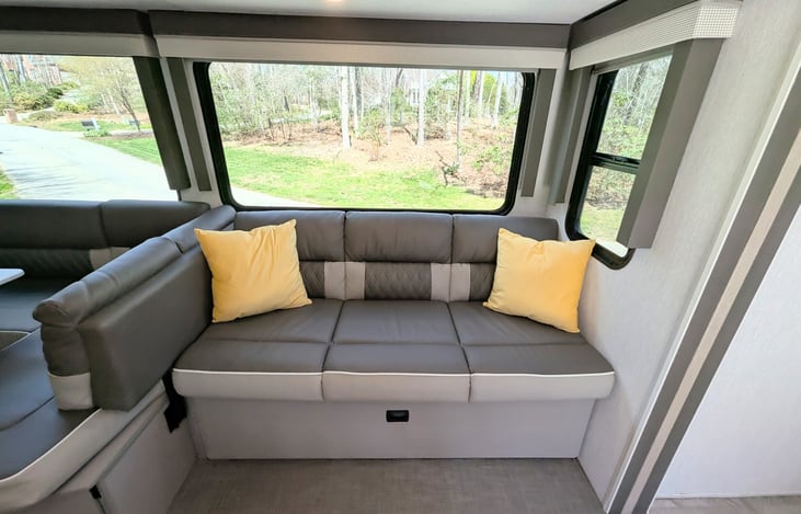 Bright and modern interior with a Custom King bed, double bunks, and a Versa-Lounge slide. Features a 30” fireplace, panoramic windows, 10.7 cu ft fridge, and a walk-in closet. Luxury camping at its f